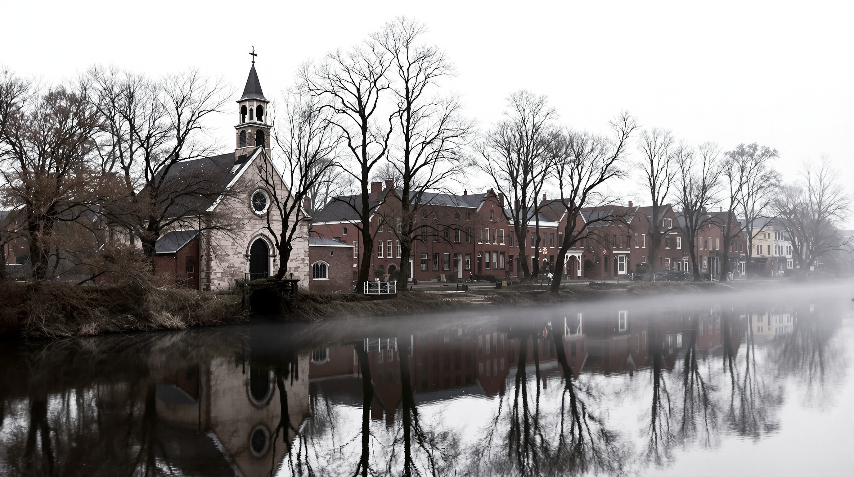 A historic stone church and old mill buildings along a quiet river at dawn