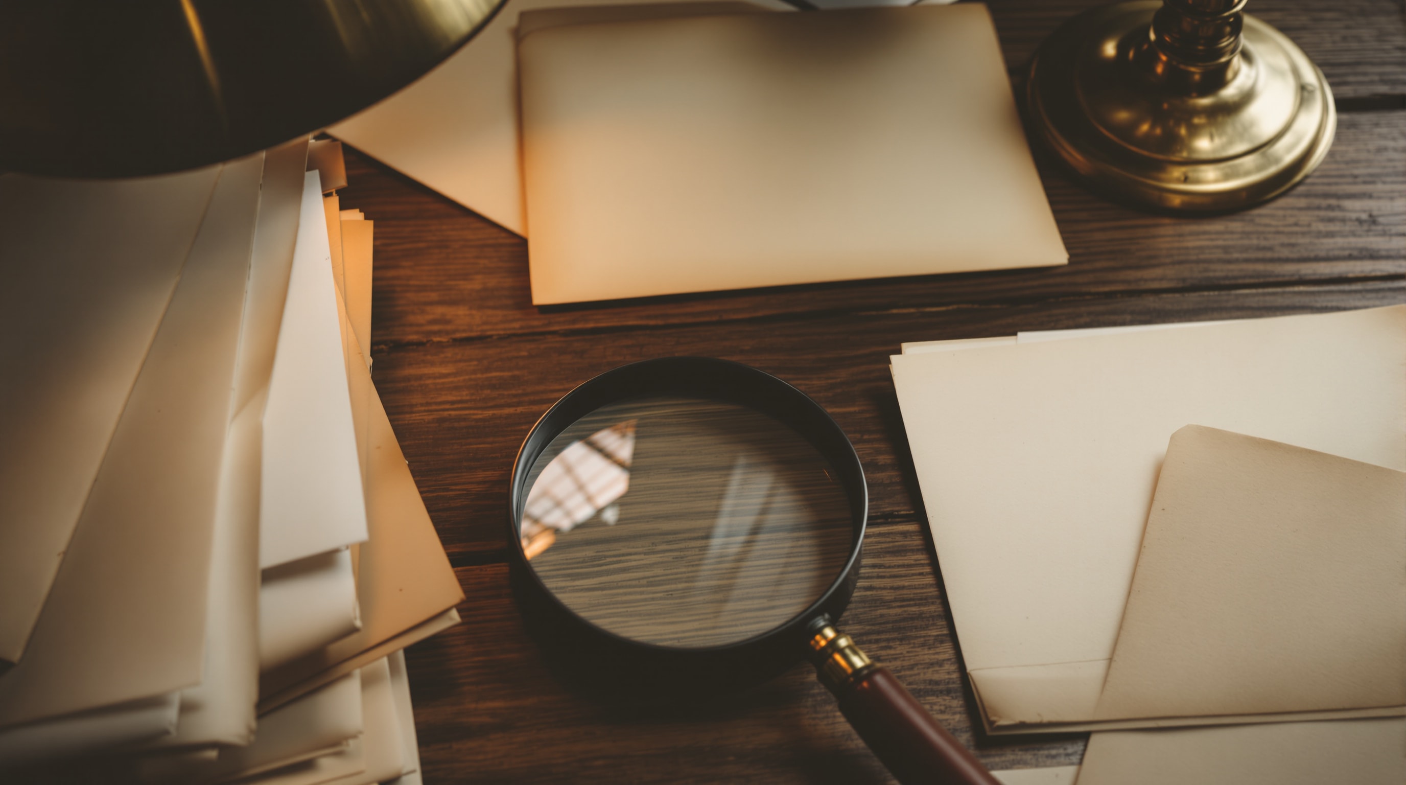 Old documents, an archival folder, and a magnifying glass on a wooden desk